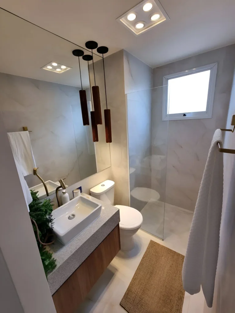 Modern small bathroom with recessed lighting, pendant lights, large mirror, and wooden vanity.