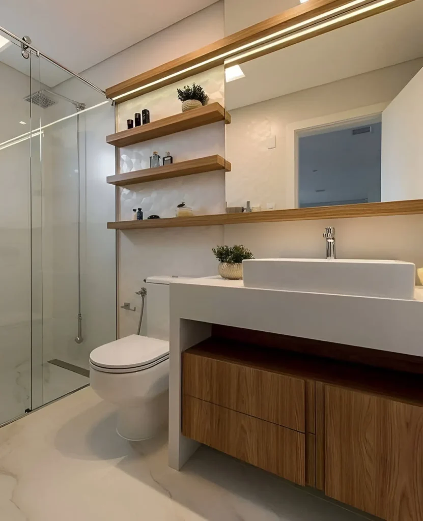 Modern small bathroom with long wooden floating shelves, white vanity, and sliding glass shower door.