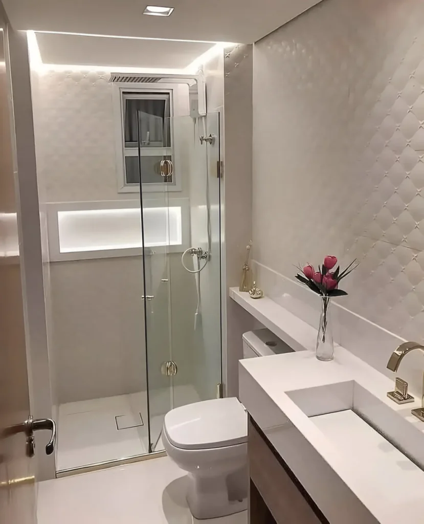 Modern small bathroom with textured white wall tiles, integrated lighting, white vanity, and glass shower door.