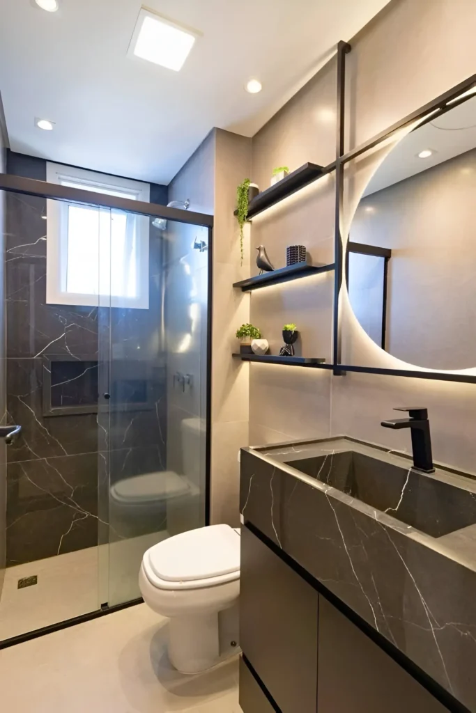 Modern small bathroom with dark vanity, large round backlit mirror, black fixtures, and light-colored floor.