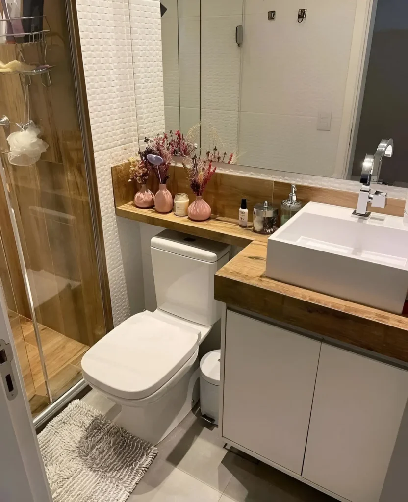 Modern small bathroom with shelf above toilet, floating white vanity, and wood-look shower accent.