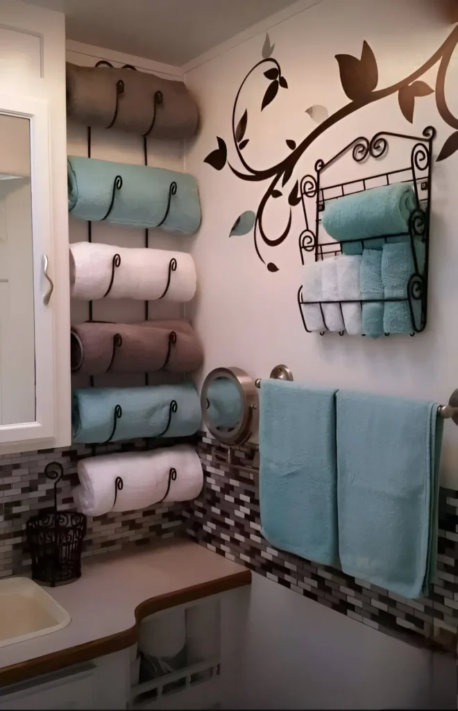 Bathroom wall with multiple horizontal towel bars on one side, a decorative metal towel rack with shelves above a standard towel bar, and a sink visible.