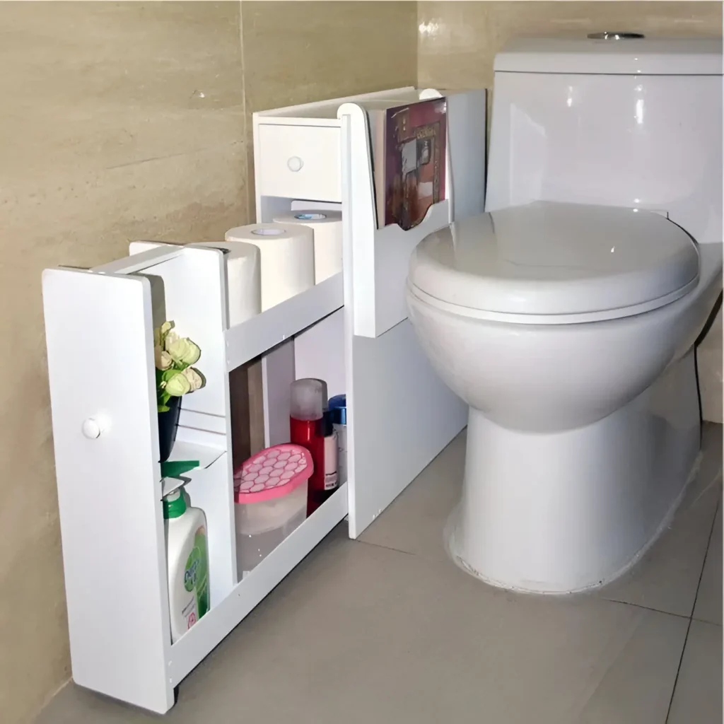 Slim white rolling cart with multiple shelves tucked beside a toilet, holding toilet paper, toiletries, cleaning supplies, and a small plant.