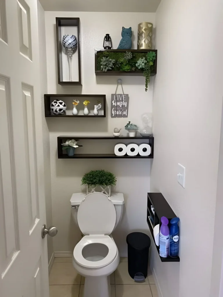 Small bathroom with multiple dark wood box shelves mounted on the wall above and beside the toilet; shelves display decorative items, plants, toiletries, and toilet paper.