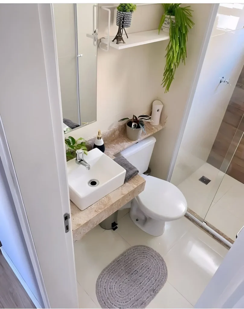 Small bathroom with a vanity countertop that extends over the back of the toilet, creating a continuous surface; a small plant and decorative items are placed on the extended portion.