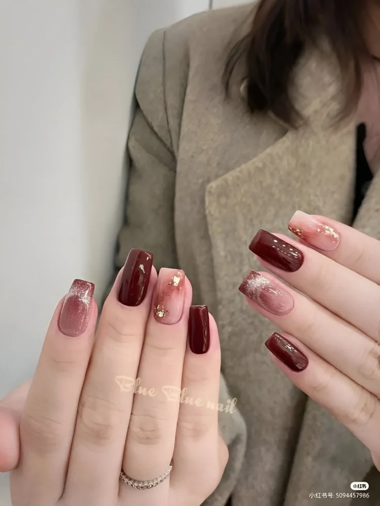 Burgundy ombre nails with gold accents for a sophisticated and stylish look.