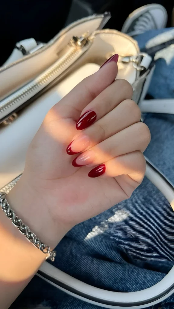 Glossy red almond nails with sheer ombre tips for a chic and elegant look.