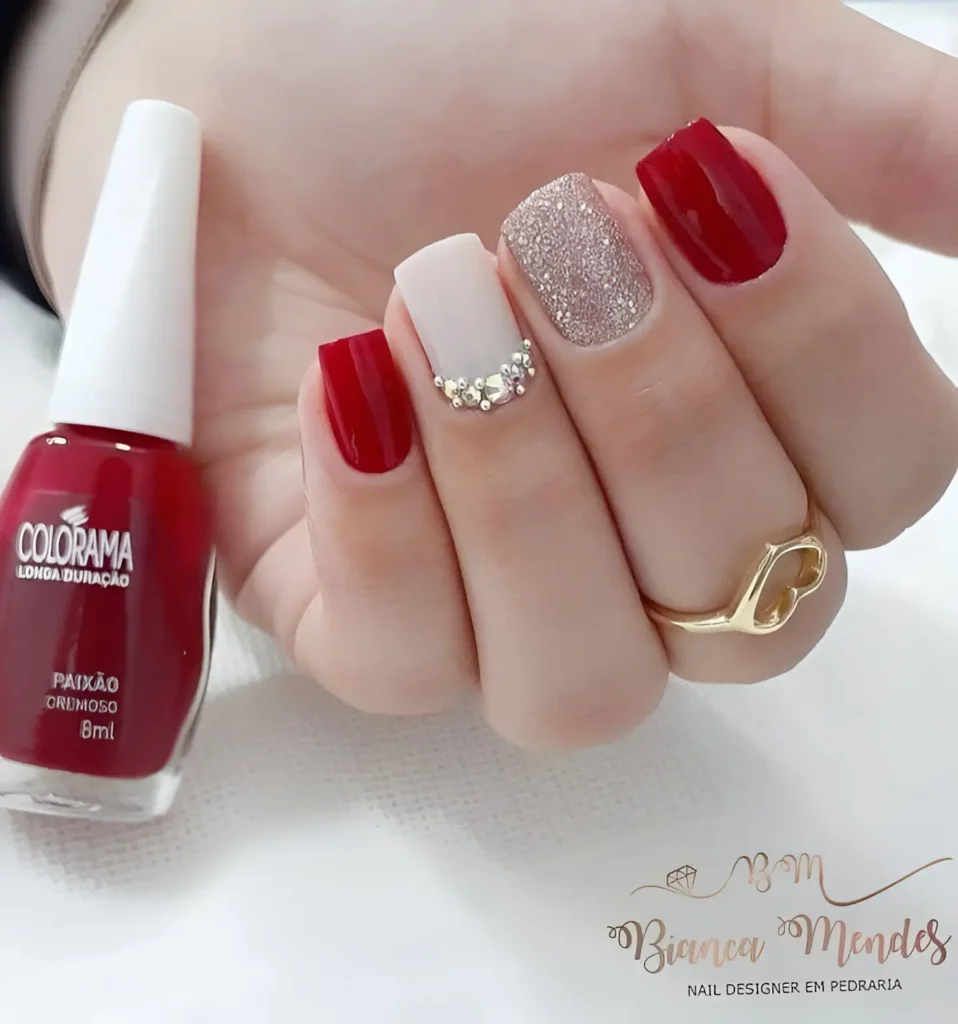 Red and nude nails with glitter and rhinestones for a glamorous and elegant look.