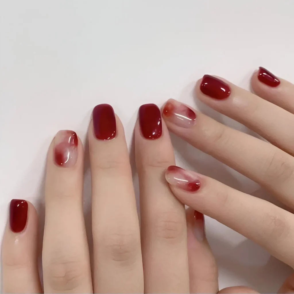 Glossy red nails with sheer watercolor accents for a soft and artistic manicure.