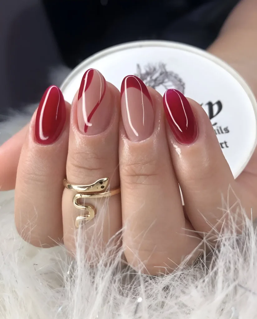 Glossy red almond nails with sheer minimalist accents for a modern and elegant look.