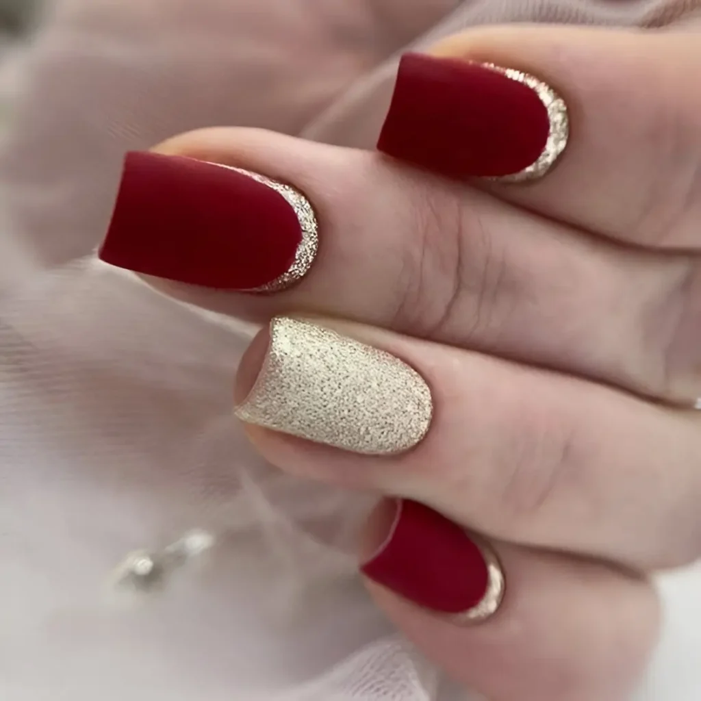 Matte red and gold nails with glitter details for a luxurious and elegant design.