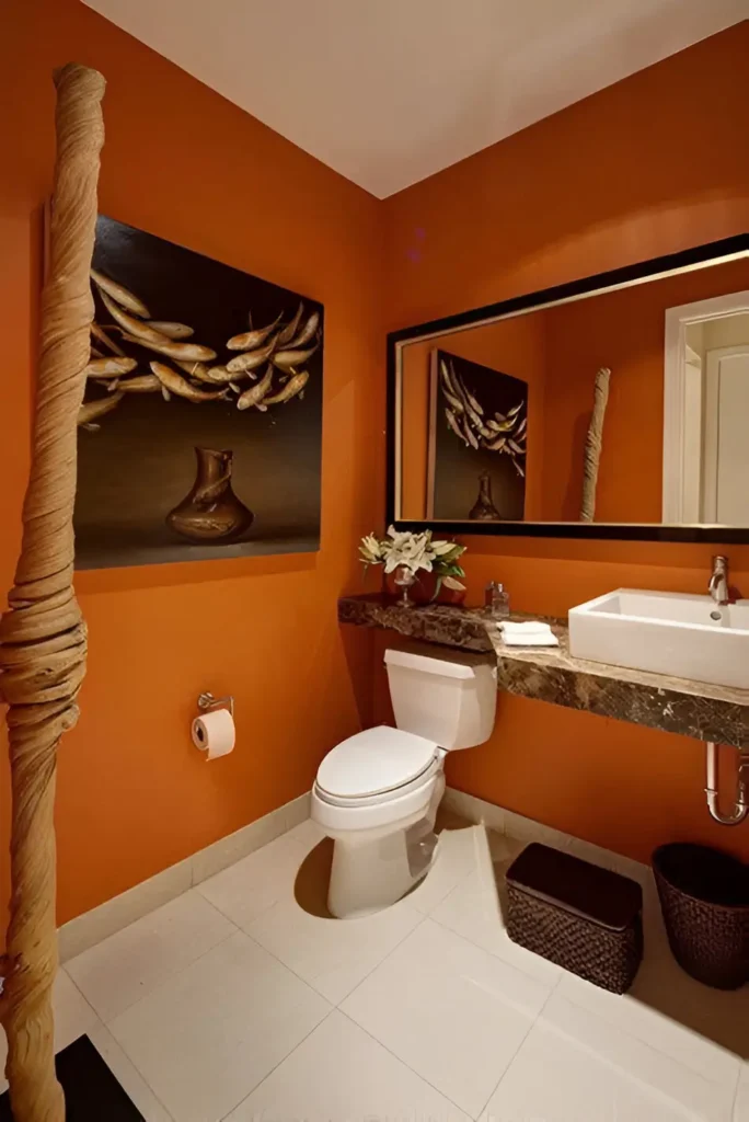 Bathroom with warm orange walls, a large framed mirror, a white sink and toilet, dark countertops, and a unique wooden decorative element.