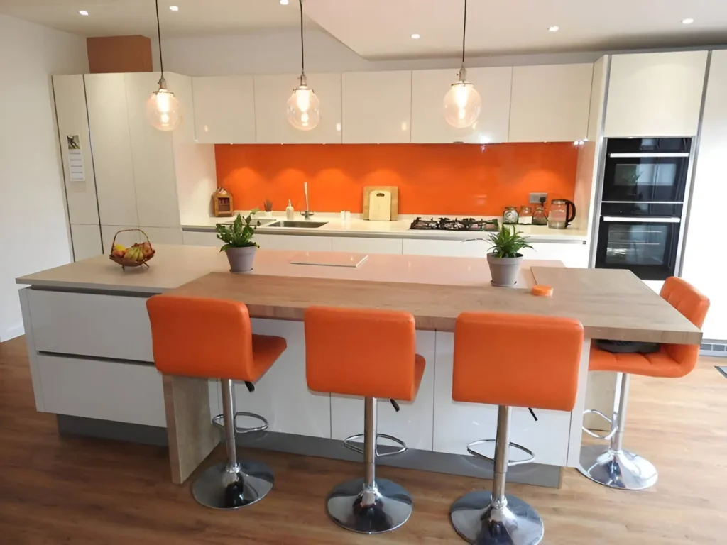 Modern kitchen with white cabinetry, a light wood countertop, an orange glass backsplash, orange bar stools, pendant lights, and stainless steel appliances.