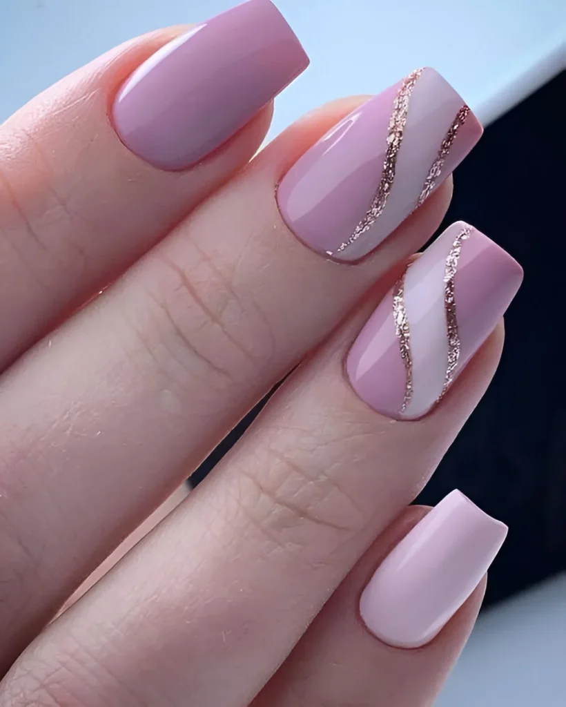 Elegant pink and white nails with gold glitter swirl accents.