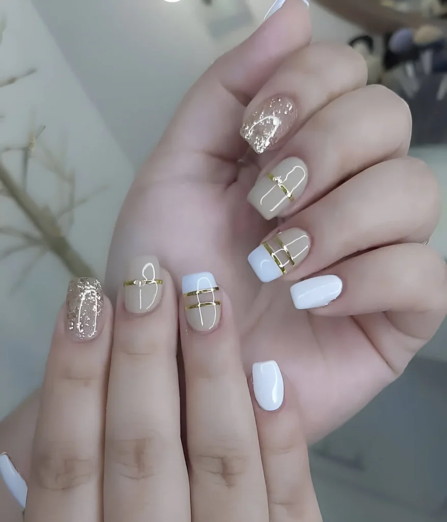 Classy neutral nails with gold stripes and glitter accents on square gel nails.