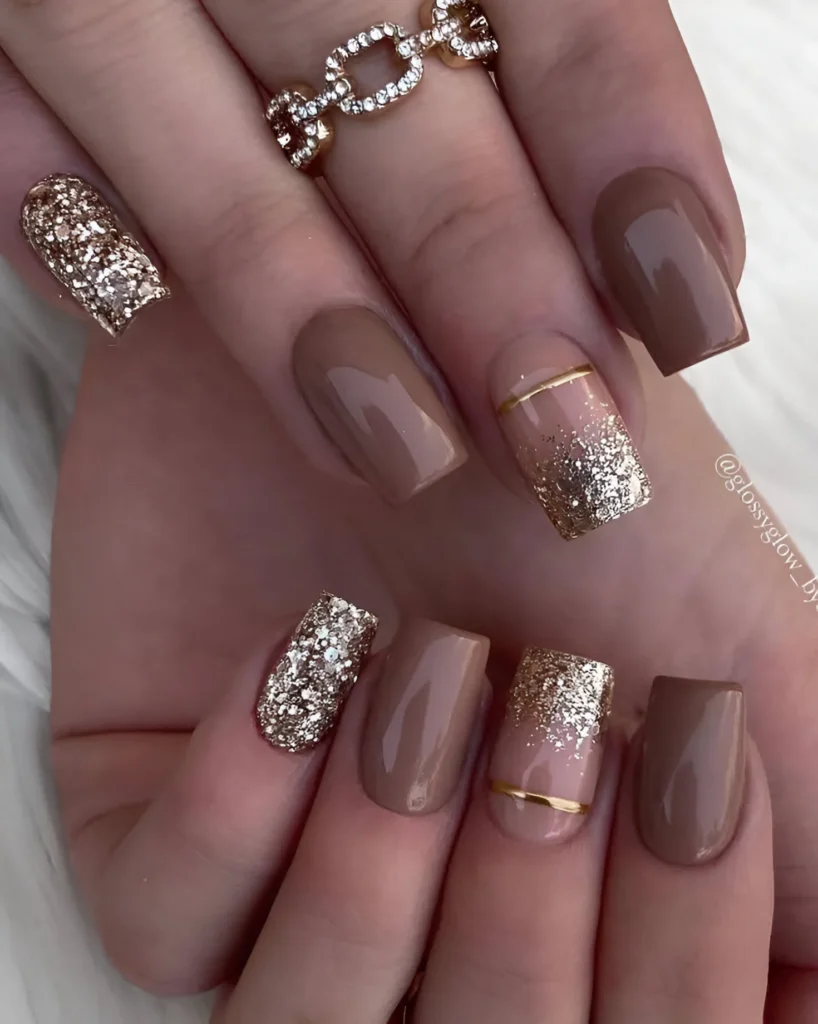 Elegant brown nails with gold glitter and striping accents.