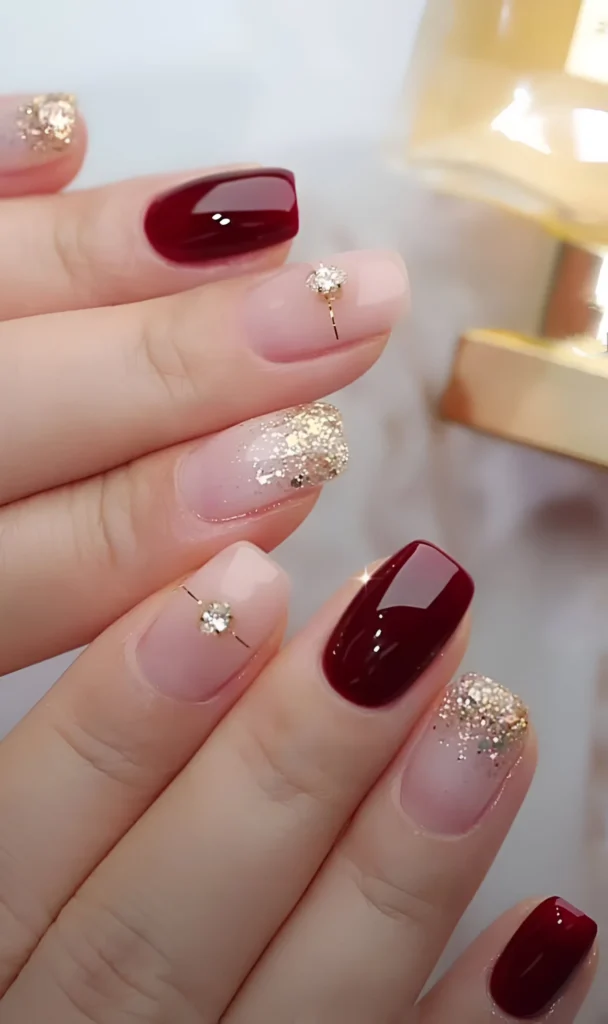 Elegant crimson and nude nails with gold glitter and rhinestone accents - elegant nail designs