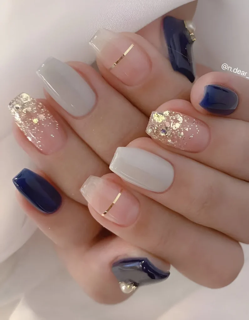 Elegant nail design featuring navy, nude, glitter, and gold stripes.