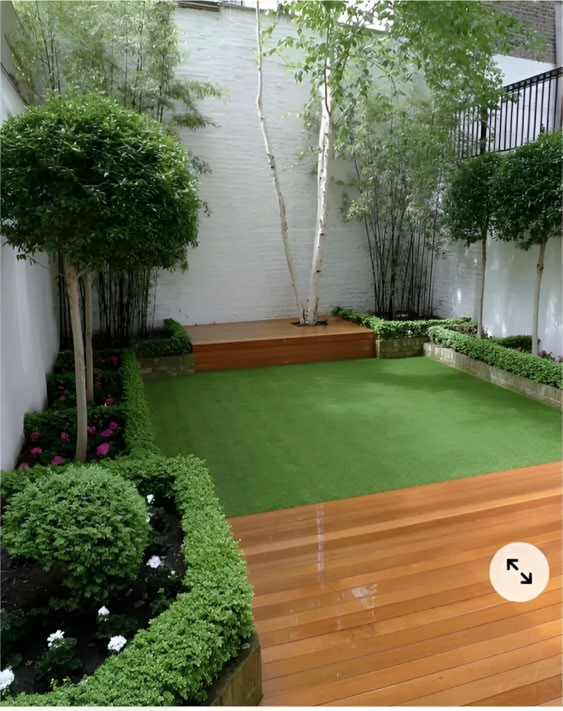 Small courtyard garden decor with multi-level wooden decking and trimmed hedges.