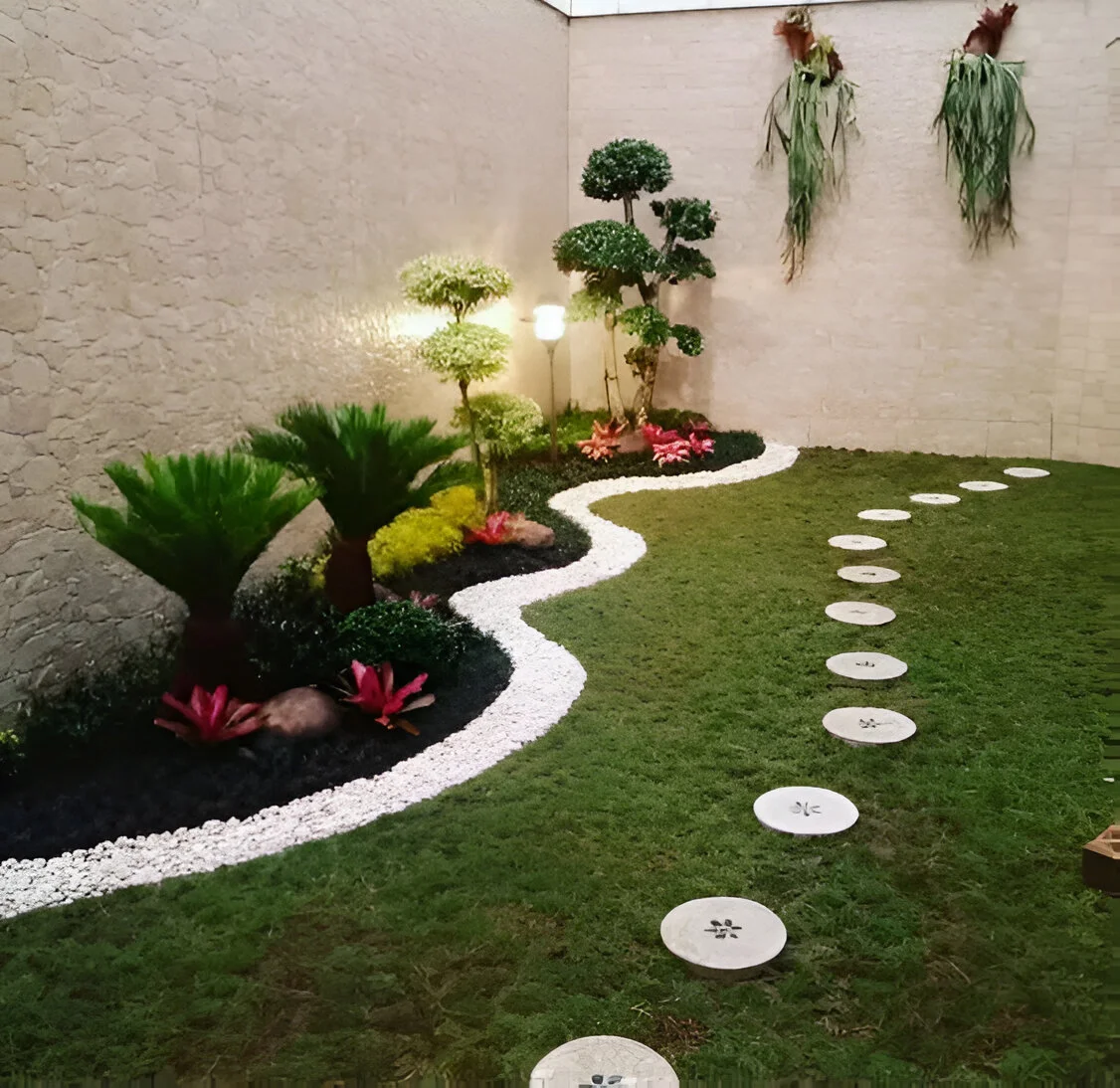 Garden decor with a winding pathway made of stepping stones, bordered by white pebbles and plants.