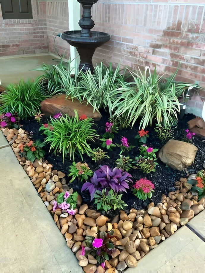 Garden decor with a tiered water fountain, colorful plants, mulch, and pebbles - amazing garden decor ideas