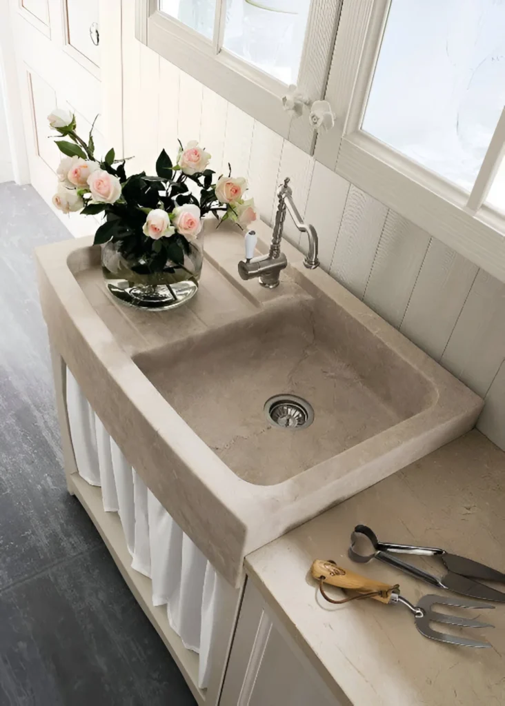 Farmhouse apron-front kitchen sink made of stone, featuring an integrated drainboard.