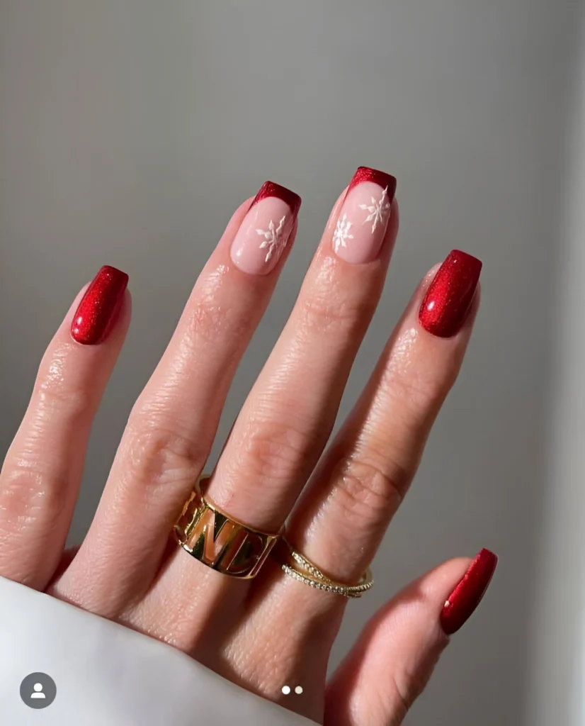 Red French tip nails with snowflake designs for a festive winter look.