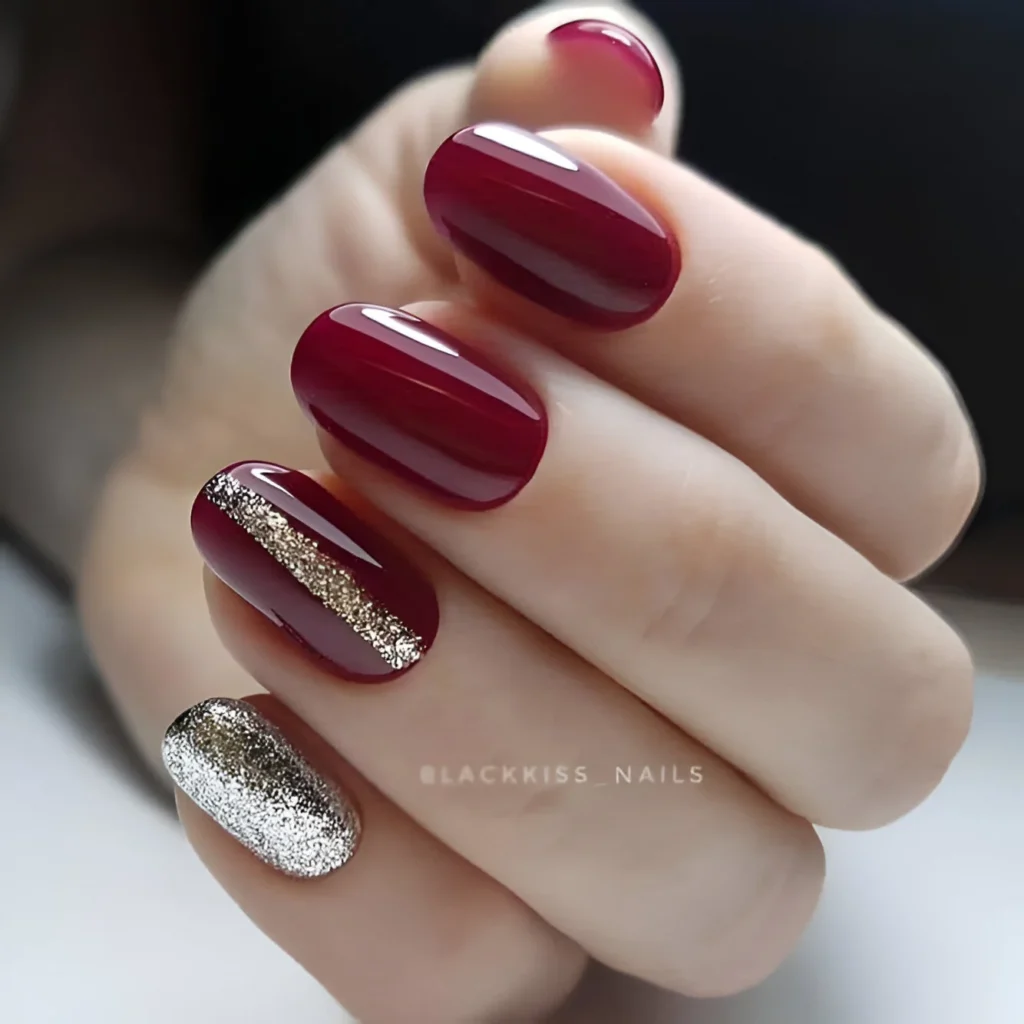 Deep burgundy nails with gold glitter accents for a luxurious manicure.