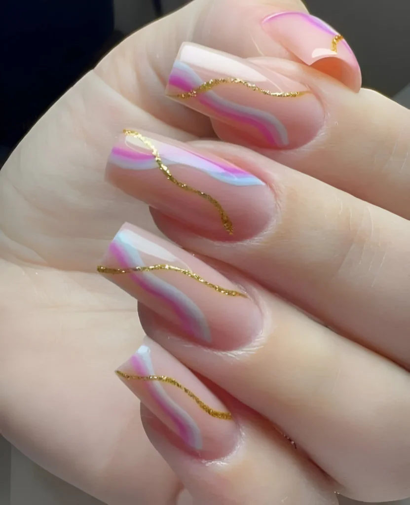 Sheer pink nails with abstract gold wave designs.