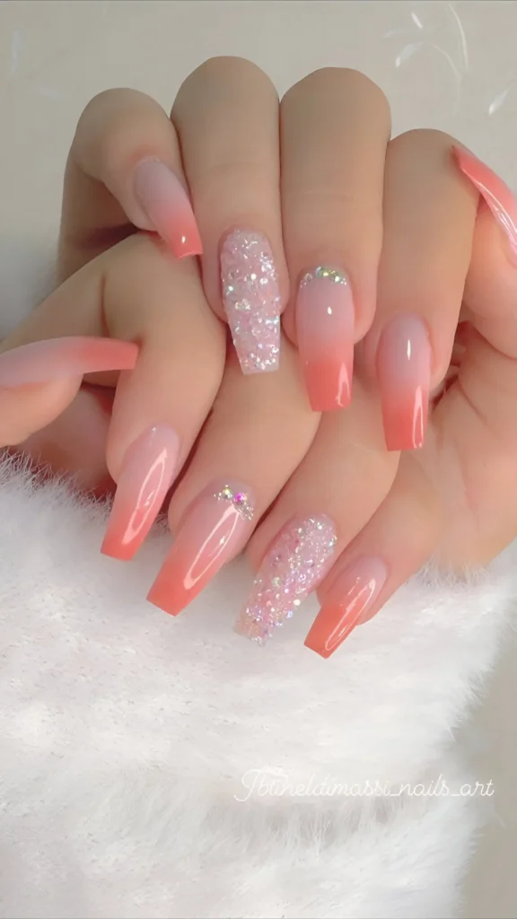 Nude to coral-pink ombre nails with chunky pink glitter accents.