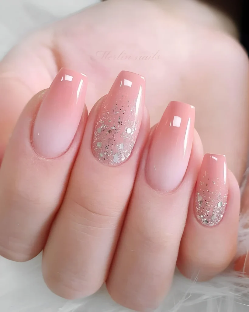 Nude to peach ombre nails with speckled glitter accent.