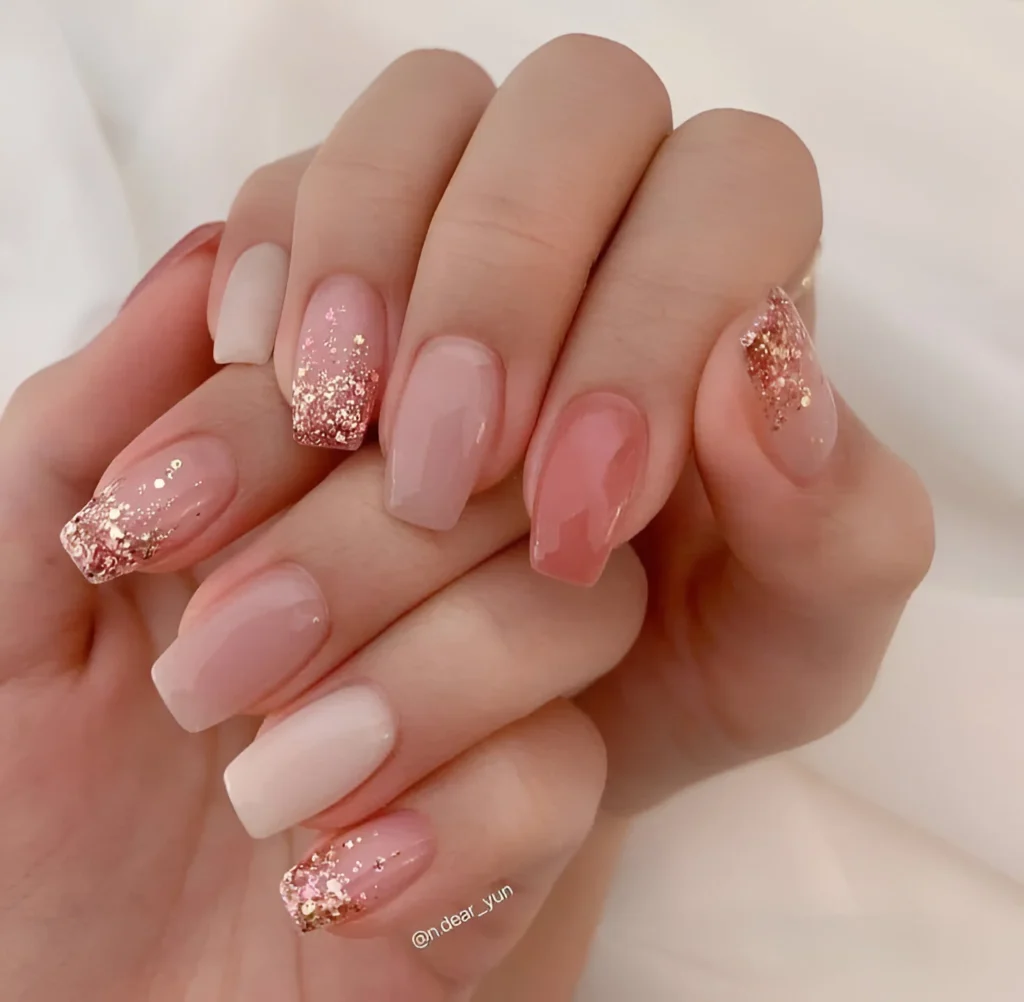 Mixed nude and light pink nails with glitter and gold foil accents.