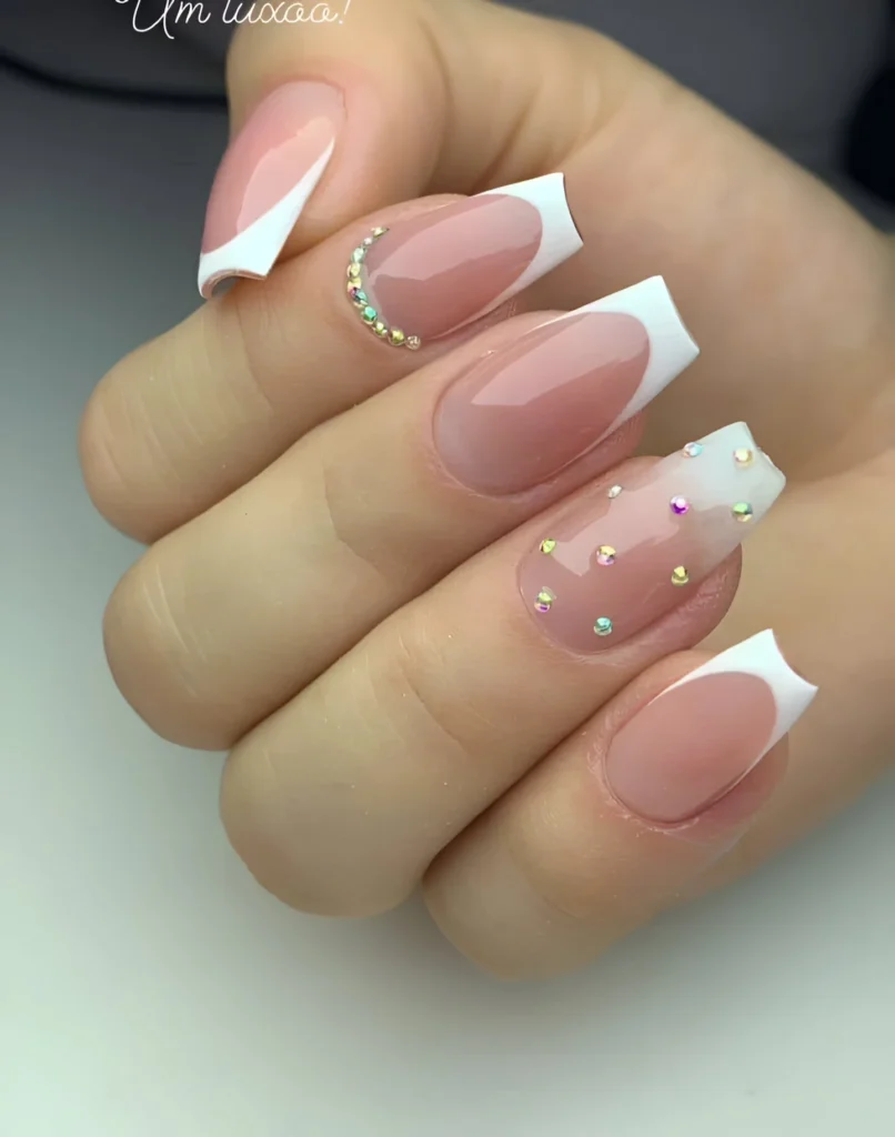 French tip nails with sheer pink base and iridescent rhinestone details.