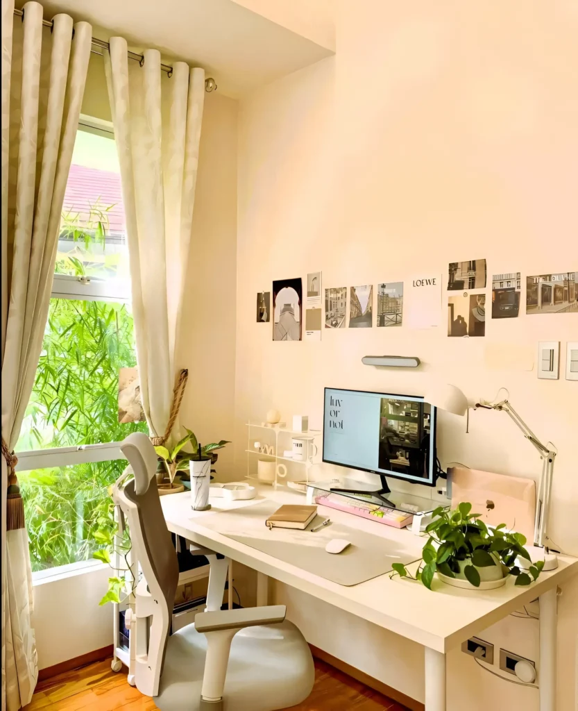 Desk setup near window with plants, computer, and neutral decor.