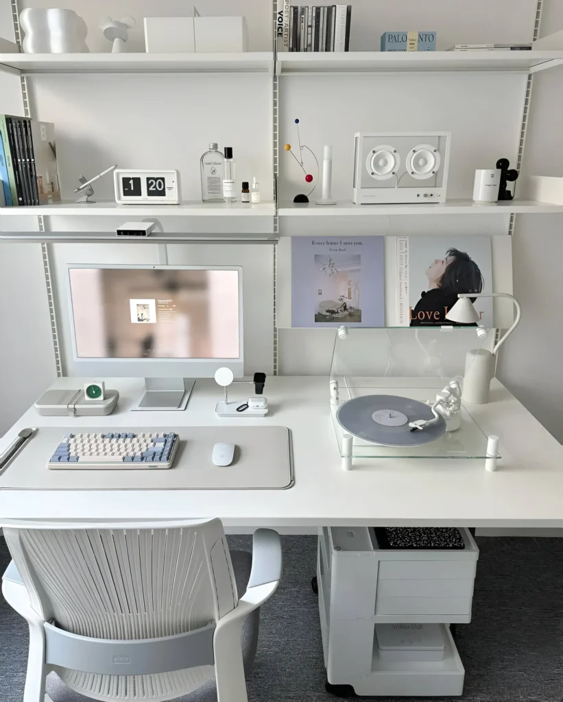 Desk setup with a monitor, keyboard, mouse, and various tech accessories, all in a white and neutral color palette.