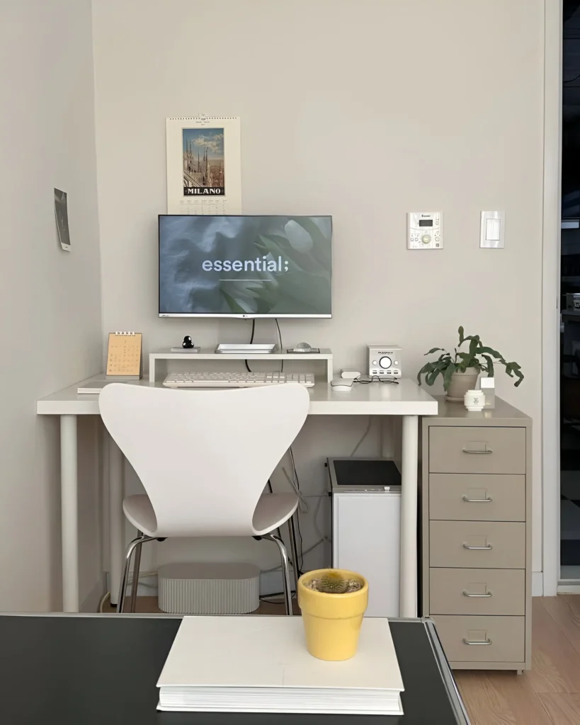 Minimalist desk setup with monitor, keyboard, chair, and a few small decorative items.