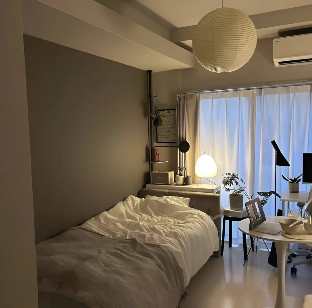 Small bedroom with a dark gray accent wall behind the bed, a large paper lantern-style pendant light, and white bedding.