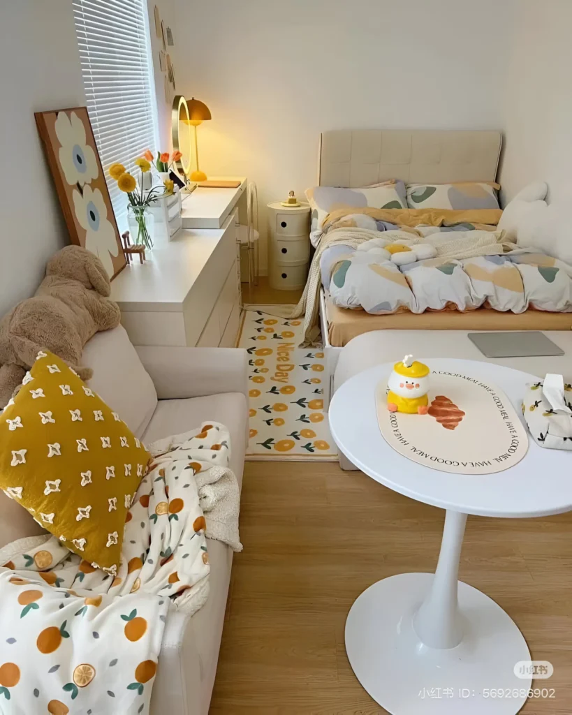 Small bedroom featuring light yellow accents in the bedding, artwork, and a throw blanket, complemented by white furniture and walls.